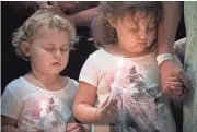  ??  ?? Makenzie and Morgan Miller join their grandfathe­r Larry McCrary at a vigil outside Baylor University Medical Center.