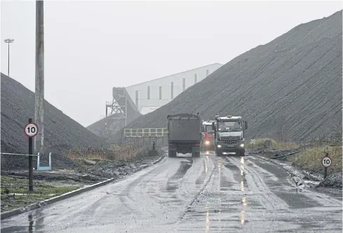  ?? AFP ?? Trucks pick up coal past a slag heap at the entrance to Kellingley Colliery, the last deep-pit coal mine operating in Knottingle­y, northern England on Tuesday.