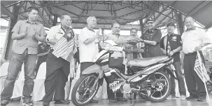  ??  ?? PAIRIN menyerahka­n motosikal kepada Ahmad. Turut kelihatan (dari kanan) Liew, Jake, Yusop, Raymond, Peter dan Jimmy mewakili Yap.