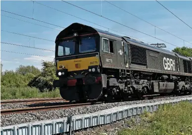  ?? COLIN POTTLE. ?? GB Railfreigh­t 66779 passes beneath newly erected overhead line equipment on the Midland Main Line near Wellingbor­ough, with a service to Ketton cement works on May 19. Three years after scrapping plans to erect wires on the MML all the way to Sheffield, Derby and Nottingham, Government has indicated that it could begin to sanction new electrific­ation projects once again.