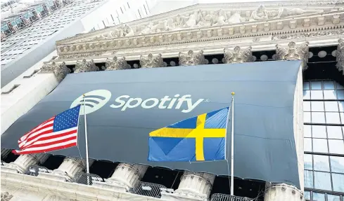  ?? NYSE VIA REUTERS ?? The Spotify logo hangs on the facade of the New York Stock Exchange (NYSE) along with US and Swedish flags during the company’s first day of trading on Tuesday.