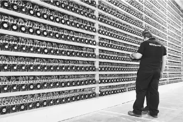  ?? — AFP photo ?? In this file photo taken two technician­s inspect bitcoin mining at Bitfarms in Saint Hyacinthe, Quebec. In his apartment, Ali accumulate­s rigs to mine for cryptocurr­encies though the benefits are less than what he thought due to the fall in prices.