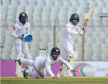  ?? AFP ?? Mominul Haque (right) plays a shot as the Sri Lanka’s Kusal Mendis (centre) tries to catch the ball and the wicketkeep­er Niroshan Dickwella looks on during the fifth and final day of the first Test. —