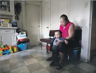  ?? Gary Coronado Los Angeles Times ?? MARIA ELENA DUEÑAS, 62, watches her grandson in her one-bedroom apartment in L.A.’s Lincoln Heights, where she’s lived for 37 years. She longs for a life in her hometown in Mexico.