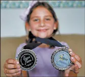  ??  ?? Brynn Hefner, 6, shows off the medals she won in her age group for participat­ing in past Bri’s RACE to End Domestic Violence events.