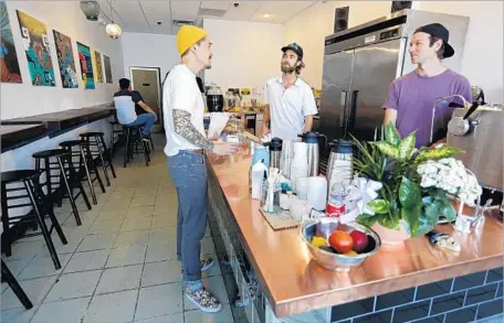  ?? Photograph­s by Gary Coronado Los Angeles Times ?? CO-OWNERS John Schwarz, center, and Jackson Defa, right, serve customers at Weird Wave Coffee in Boyle Heights. It opened June 15.