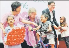  ??  ?? Julini (centre) handing over the prizes to children (from left) Nur Azwa Shafina, 6, Hanani Firdaus Sumari, 7 and Nur Qalesya Damia Mohd Yusuf, 5 at the Nu Skin Malaysia-IJN Foundation Wish List Project 2016. Also seen is a member of IJN Foundation...