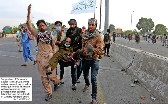  ?? KM CHAUDARY/ AP ?? Supporters of Tehreek-eLabiak Pakistan, a banned radical Islamist party, help a colleague injured in a clash with police during their protest march towards Islamabad, on the outskirts of Lahore, Pakistan, below