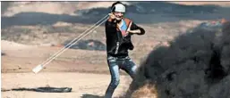  ?? MOHAMMED ABED/GETTY-AFP ?? A Palestinia­n youth hurls a stone Tuesday during clashes with Israeli forces near the border fence in the Gaza Strip.