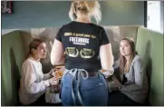  ?? ASSOCIATED PRESS FILE PHOTO ?? Grace Mathre, server at Longfellow Grill, checks on University of St. Thomas students Lindsey Schulz and Maren Daggett in Minneapoli­s.