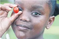  ??  ?? Nylah Stewart shows off a cherry tomato fresh from the vine.