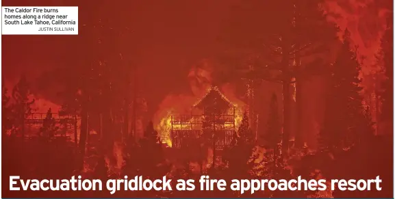  ?? JUSTIN SULLIVAN ?? The Caldor Fire burns homes along a ridge near South Lake Tahoe, California