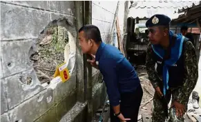  ??  ?? Terrifying damage: Thai police inspecting a hole in the wall after the bomb attack at a civilian volunteer base in Rangae, Narathiwat. — AFP