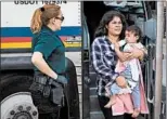  ?? LOREN ELLIOTT/GETTY-AFP ?? A woman carries a baby as migrants are dropped off last month at a bus station after being released in Texas.