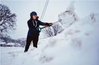  ?? Carolyn Kaster/Associated Press ?? Graphic designer Emily Brewer shovels out her driveway early Friday to drive to work in Sioux City, Iowa. Arctic air is expected to arrive in the South by this weekend.