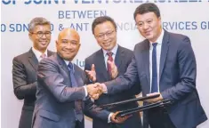  ?? ASYRAF RASID/THE SUN ?? Touch 'n Go CEO Syahruniza­m Samsuddin (left) exchanges documents with Alipay’s general manager for Southeast Asia, Dayong Zhang. Looking on are Tengku Zafrul (left) and Ant Financial group CEO Eric Jing.