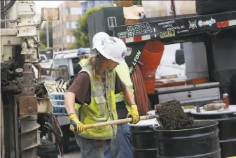  ?? Photos by Lea Suzuki / The Chronicle ?? Workers at 1776 Green St. place dirt removed from the sidewalk in barrels on Tuesday. The site of an auto repair garage contaminat­ed by benzene is being converted to housing.