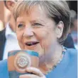  ?? FOTO: DPA ?? Angela Merkel trinkt bei der Stralsunde­r Stadtwache ein Bier.