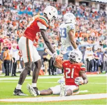  ?? DAVID SANTIAGO dsantiago@miamiheral­d.com ?? Hurricanes running back Henry Parrish Jr. is helped up by Jaleel Skinner after scoring a touchdown on Saturday.