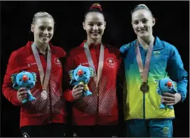  ?? AP PHOTO/DITA ALANGKARA ?? Silver medalist Elsabeth Black of Canada, left, Gold medalist Shallon Olsen of Canada, center, and Emily Whitehead of Australia, pose for photograph­s from the podium after winning the vault event of the artistic gymnastics women's apparatus final at...