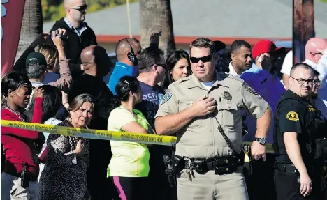  ?? FREDERIC J. BROWN/AFP/GETTY IMAGES ?? A crowd gathers behind a police line near the scene of a mass shooting that left at least 14 dead in San Bernardino, California on Wednesday.