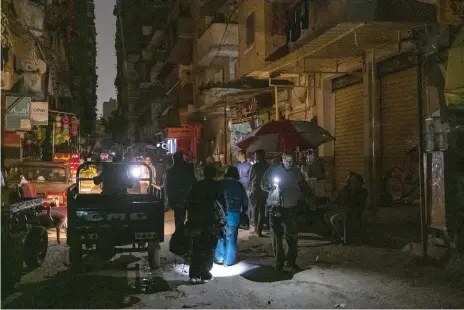  ?? AFP ?? Egyptians use flashlight­s on a darkened street in Alexandria’s Fleming district after the interrupti­on of power supplies