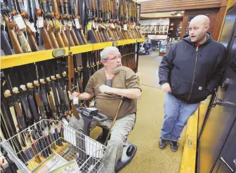  ?? APFILEPHot­o ?? BUSINESS AS USUAL: Jerry Lyons, left, talks with Pat Ison at a Cabela’s store in Dundee, Mich. Cabela’s is among several retailers that continue to sell assault-style rifles.