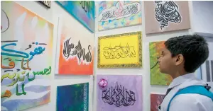  ?? Photos by Leslie Pableo ?? A student checks out entries submitted as part of the calligraph­y contest during the ‘Living Arabic’ event held at Jebel Ali School, Dubai, on Saturday. —