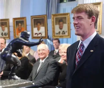  ?? AP FILe ?? MORE HONORS: USC quarterbac­k Carson Palmer, right, smiles at the Heisman Trophy after being named the 2002 Heisman Trophy winner at The Yale Club in New York. Carson is among 13 players and coaches who will be inducted into the College Football Hall of Fame in December.