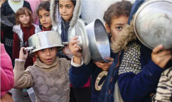  ?? Reuters ?? Palestinia­n children queue for food at a charity kitchen in Rafah, southern Gaza, amid shortages in supplies as the conflict between Israel and Hamas rages on