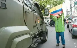  ?? DOLORES OCHOA/AP ?? A supporter of former Ecuadorian Vice President Jorge Glas protests Saturday as a military vehicle transports the ex-politician from the detention center in Quito, Ecuador, where he was held following his arrest at the Mexican Embassy in the city.