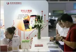  ?? PROVIDED TO CHINA DAILY ?? A staff member of Beijing Rural Commercial Bank introduces the company’s mobile app to a client at the 2nd China (Beijing) Internatio­nal Internet Era Exposition.