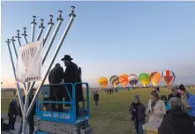 ?? ADOLPHE PIERRE-LOUIS/JOURNAL ?? Mayor Tim Keller, left, prepares to light the Hanukkah candle with the assistance Rabbi Chaim Schmukler, of Chabad of New Mexico, during last year’s Hanukkah celebratio­n at Balloon Fiesta Park.