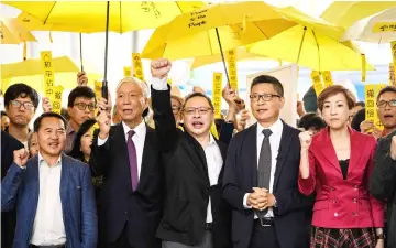  ??  ?? Chu (second left), Benny (centre), Chan (second right) and other pro-democracy campaigner­s chant before entering the West Kowloon Magistrate­s Court in Hong Kong. — AFP photo