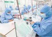  ?? PATTARAPON­G CHATPATTAR­ASILL ?? Workers make face masks at a factory in Nonthaburi. Kasikorn Securities warns of a sharp SET correction if the coronaviru­s outbreak leads to a recession.