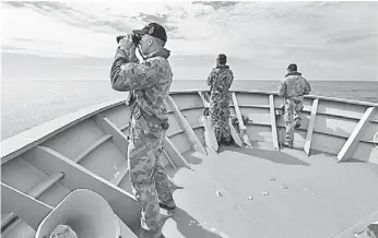  ??  ?? Gunner Richard Brown (left) of Transit Security Element looks through binoculars as he stands on lookout with other crew members aboard the Australian Navy ship HMAS Perth as they continue to search for missing Malaysian Airlines flight MH370 in this...