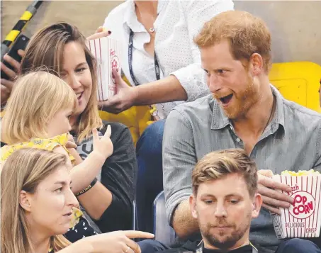  ?? Picture: GETTY ?? Prince Harry has a bit of fun with Emily Henson, left, playing hard to get with a box of popcorn. The prince was with paralympia­n David Henson and his wife Hayley, left, during the Sitting Volleyball Finals at the Invictus Games in Toronto, Canada.