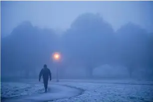  ?? (AFP/Getty) ?? A wa l ker makes their way through fog on a frosty morning in Primrose Hi ll in north London