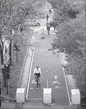  ?? AP/ANDRES KUDACKI ?? A bicyclist approaches concrete barricades Friday on a Manhattan bike path near the scene of an attack Tuesday that left eight people dead when a man drove a truck through bikers on the path.