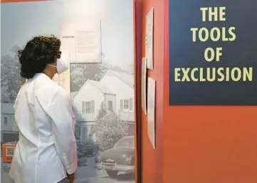  ?? NAPERVILLE HERITAGE SOCIETY ?? A visitor reads through a display at the new exhibit “Unvarnishe­d: Housing Discrimina­tion in the Northern and Western United States” at the Naper Settlement.