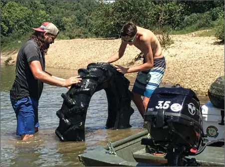  ?? (Special to the Democrat-Gazette/Michael and Tonya Sacomani) ?? Michael Sacomani (left) and son Mason check out the tractor tire they pulled from the Saline River during the covid-19 pandemic.