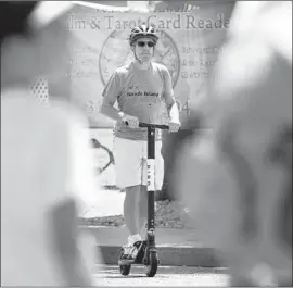  ?? Christina House Los Angeles Times ?? A SCOOTER user shares a crosswalk with pedestrian­s in Venice Beach. A lawsuit alleges e-scooters contribute to pedestrian injuries and contain defectives parts.