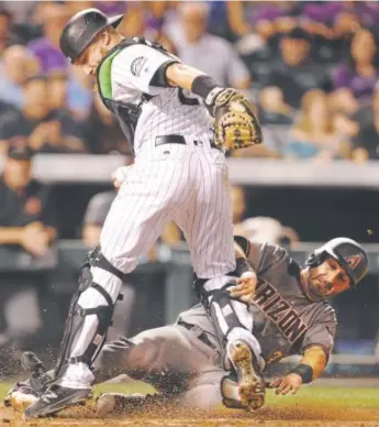  ?? Joe Mahoney, Getty Images ?? Daniel Descalso of the Diamondbac­ks slides into an out on a force play at the plate against the Rockies and their catcher, Jonathan Lucroy, during Saturday’s game.