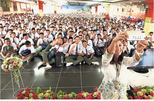  ??  ?? Royal support: Tengku Zatashah taking a picture during the assembly with students of SMK Rantau Panjang Klang at the school hall.