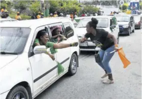  ?? ?? Jamaica Labour Party supporters in a motor car greeting a People’s National Party supporter outside the Chapelton Family Court in Clarendon North Central, Thursday.