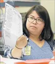  ?? Rich Pedroncell­i Associated Press ?? SAN LI, a worker at the Sacramento County registrar’s office, inspects a mail-in ballot in June.