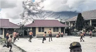  ?? AFP VIA GETTY IMAGES ?? Top: Elementary schoolchil­dren play outside of their classrooms as Mount Sinabung erupts. Many residents in the area have been forced to relocate to other villages in Northern Sumatra at a safer distance from the volcano, one of the most active in Indonesia.