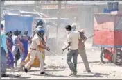  ?? ANI ?? Policemen lathicharg­e a migrant worker after a clash erupted between migrant workers and police in Surat on Monday.