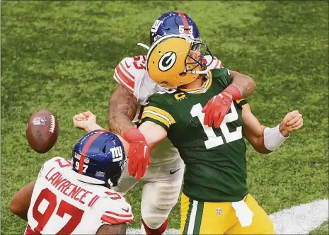  ?? Mike Hewitt / Getty Images ?? The Green Bay Packers’ Aaron Rodgers (12) is sacked by the New York Giants’ Oshane Ximinesand fumbles the ball in the fourth quarter Sunday at Tottenham Hotspur Stadium in London.