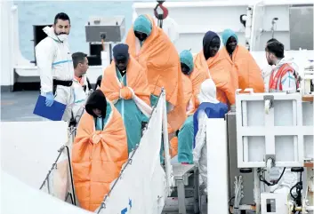  ?? GIOVANNI ISOLINO/ GETTY IMAGES ?? Migrants disembark from the Italian Coast Guard vessel Diciotti on Monday in Catania, Italy, following a rescue operation at sea. At least 64 people are feared to have drowned in a shipwreck off Libya after a dinghy, possibly carrying some 150 migrants, ran into trouble.